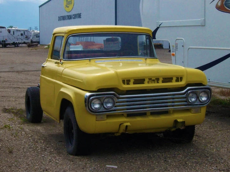 an older yellow truck is parked on a lot