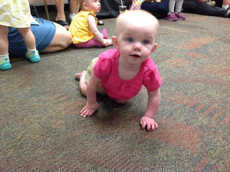 a small baby in pink shirt laying on the ground