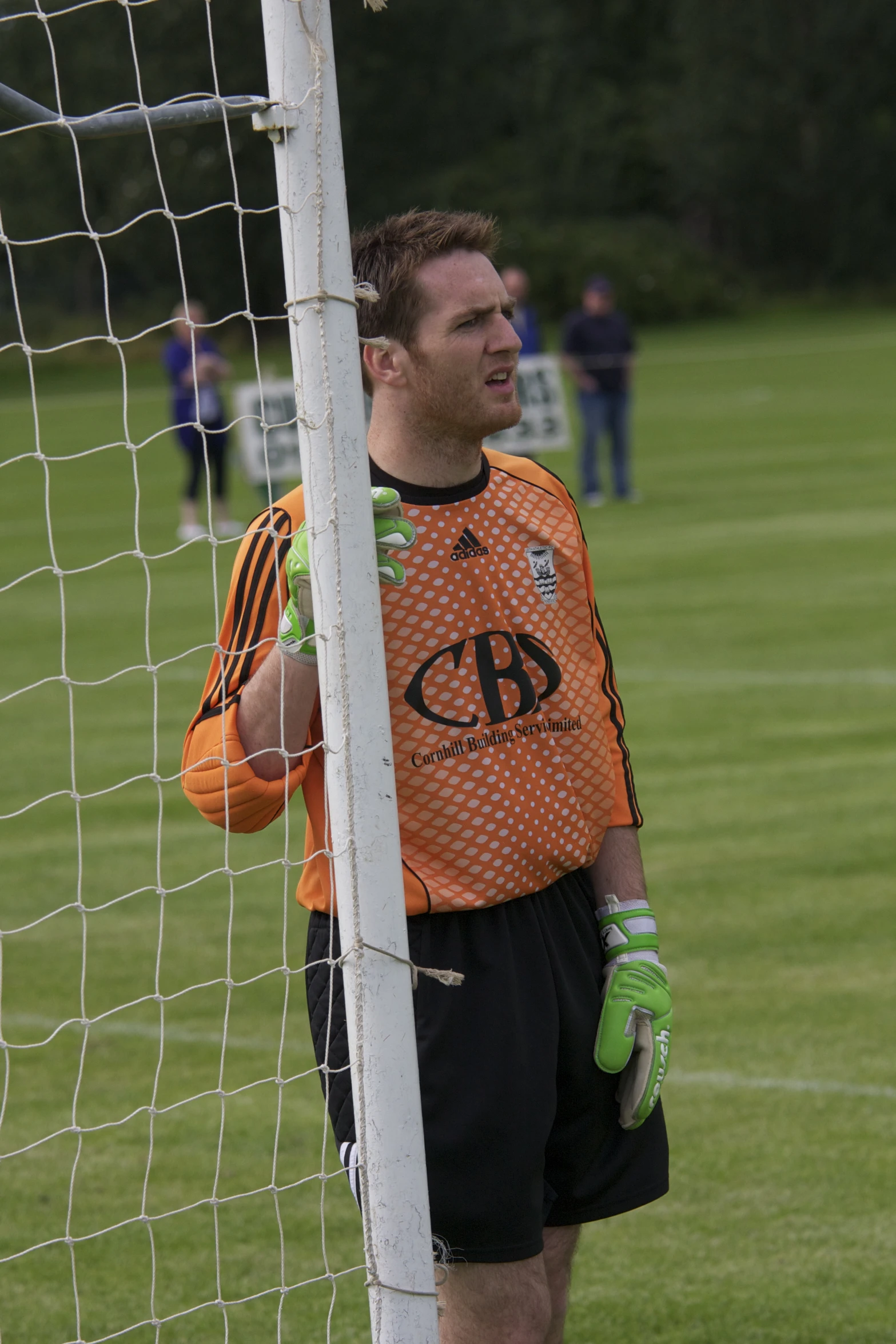 a man in orange jersey standing by the goal