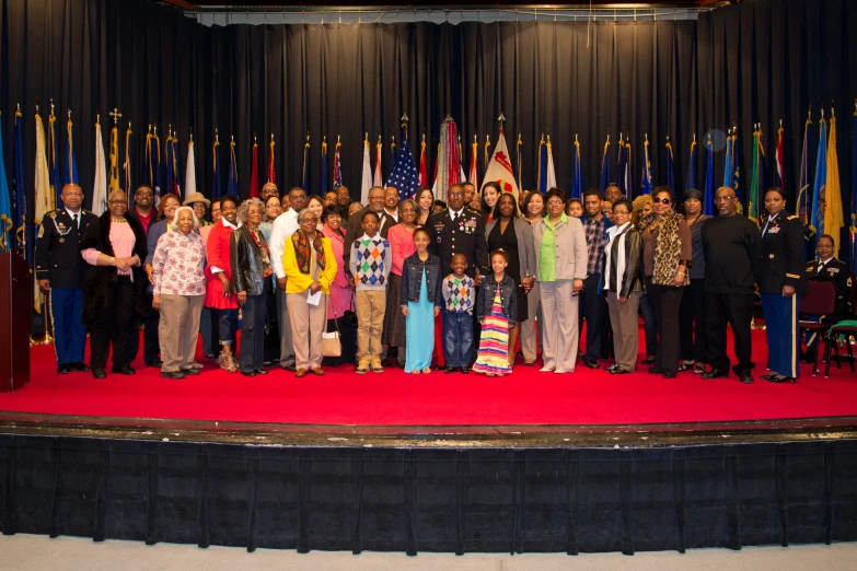 a group of people posing for a po on stage with many flags