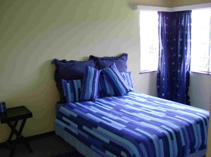 a bed in front of two windows with striped pillows on it