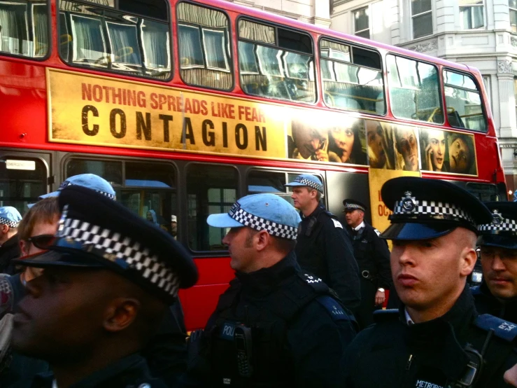 a red double decker bus driving past some police