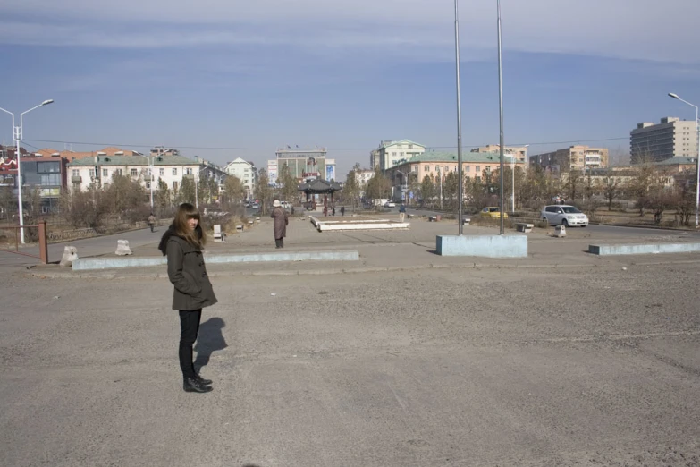 a young woman is on a cell phone as people walk by in a parking lot