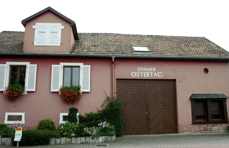 a large red building with shutters on the windows and plants growing out of the windows