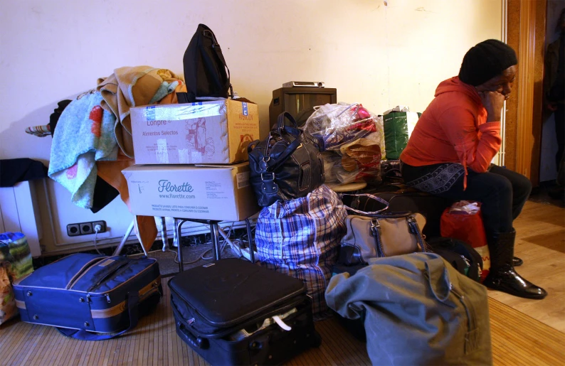 a woman sitting on a chair in front of piles of luggage