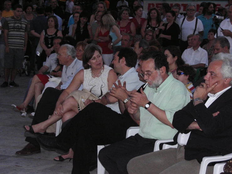 a group of people sitting in chairs in front of a crowd
