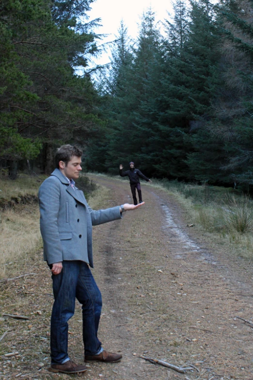 a man pointing out his hand towards a woman walking in the forest