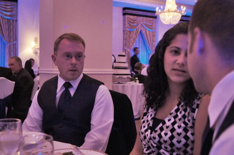 a couple and a man in dress attire are sitting down