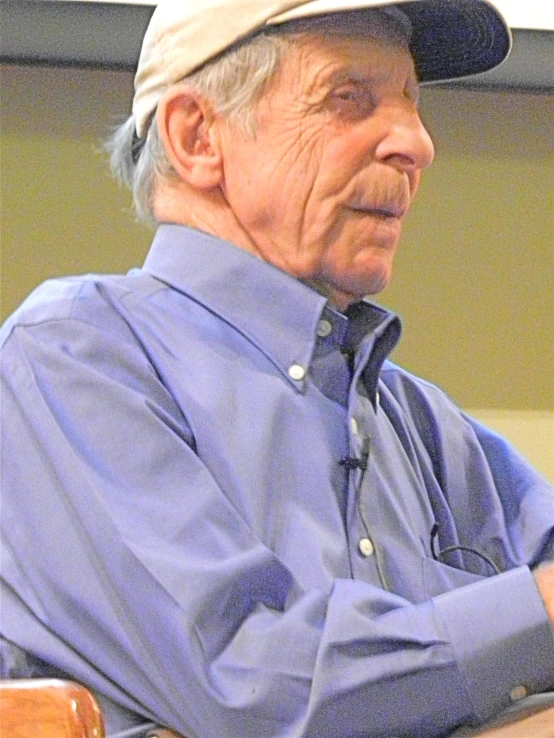 an elderly man wearing a hat and sitting down