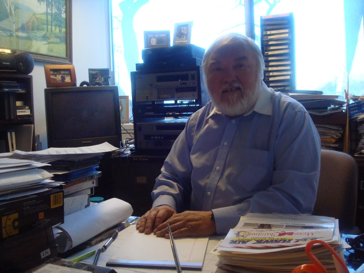 a bearded man sitting at a desk in his office