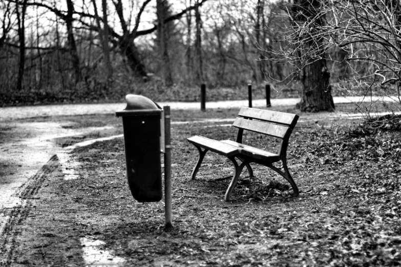 black and white pograph of a park bench and trash can