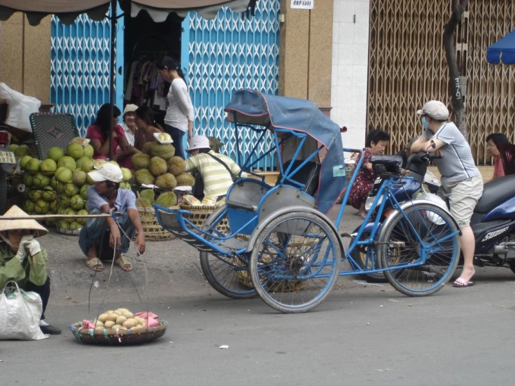 a person on a bike with baskets of fruit in front of a cart