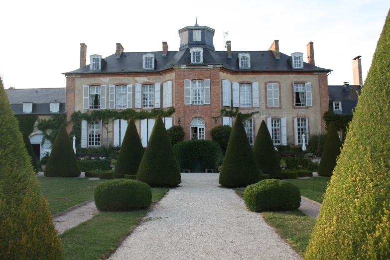 a large brick building with tall green trees and bushes