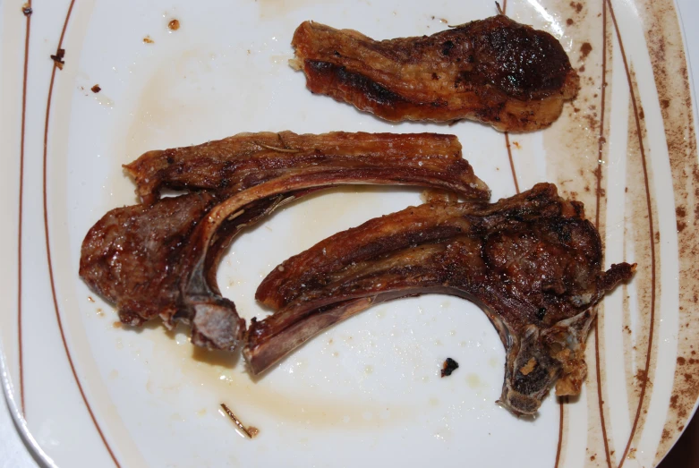 raw ribs are on a plate with brown streaks