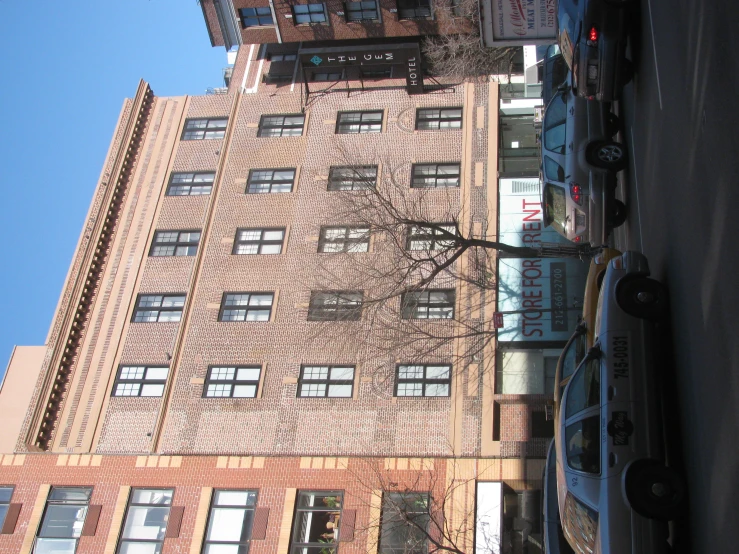 a row of four story buildings along side a street with parked cars