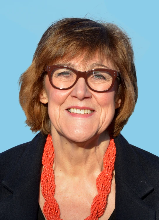 a woman wearing a black blazer with orange necklace