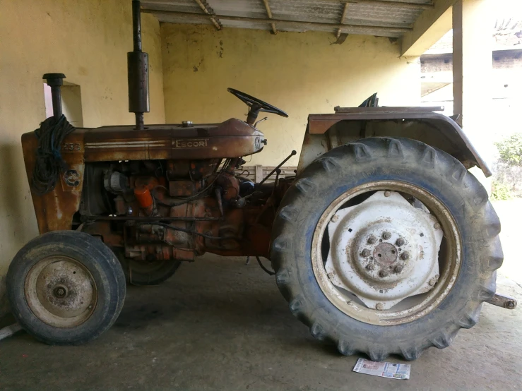 a rusted out tractor sitting under a shelter