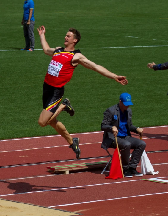 the man is in mid air while jumping over a wooden jump beam