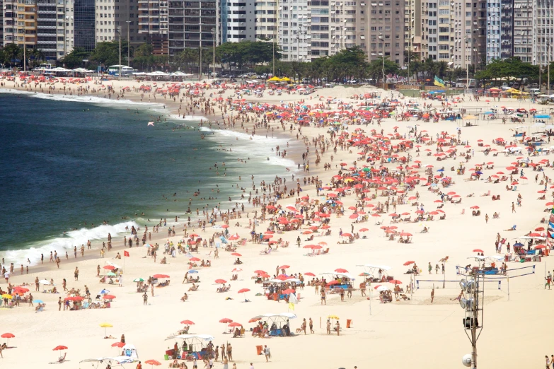 many people at the beach with large red umbrellas