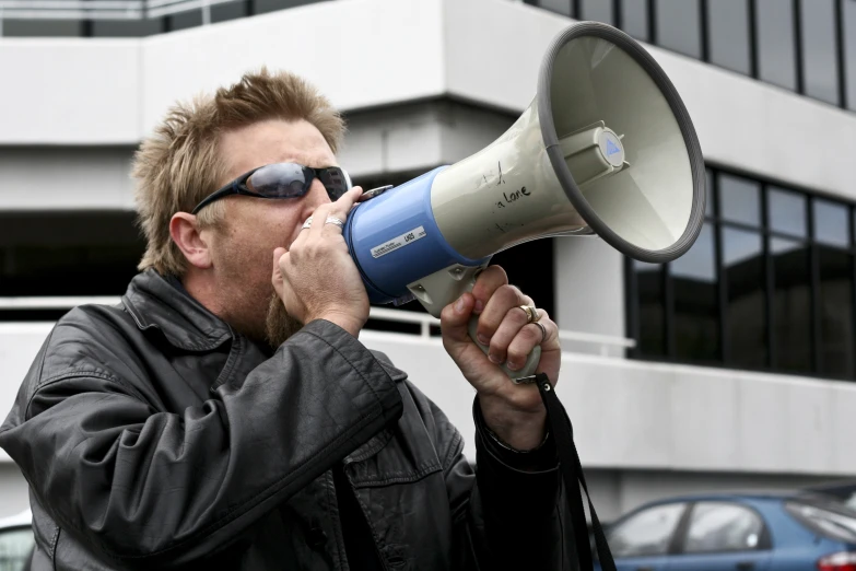 a man holding a megaphone and wearing a leather jacket