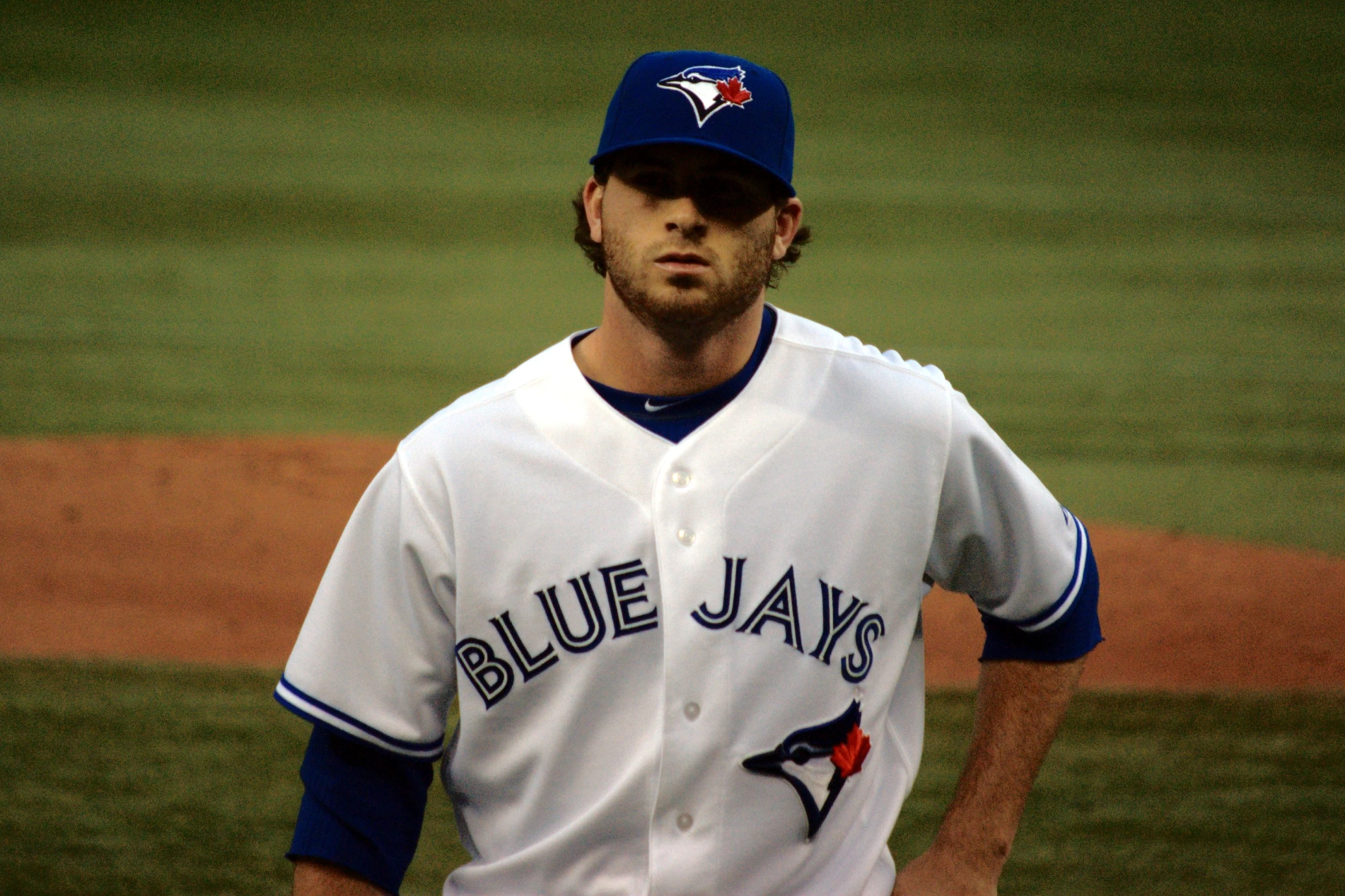 a man in white and blue baseball uniform standing by a baseball field