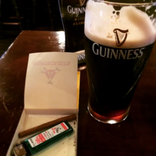 some drinks on a wooden table with some papers and a cigarette