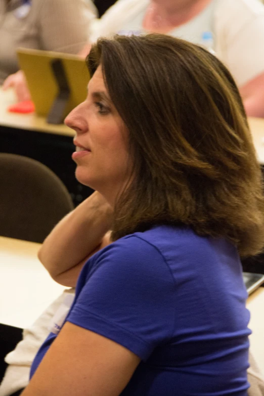 a woman sitting in front of a microphone at a lecture