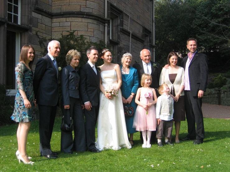 the bride and groom stand with their four children outside of a building