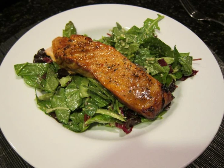 this plate features fish and greens on a table