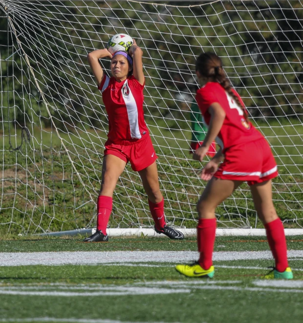 two girls playing soccer during the day on a grass field