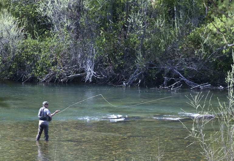 the person is fly fishing in the shallow water