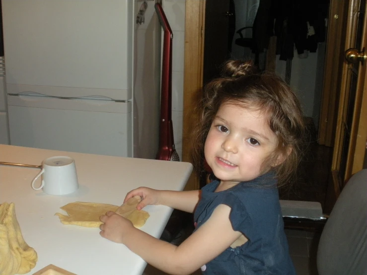 little girl sitting at the table making cookies