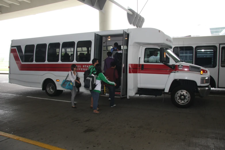 people entering the large shuttle bus at an airport