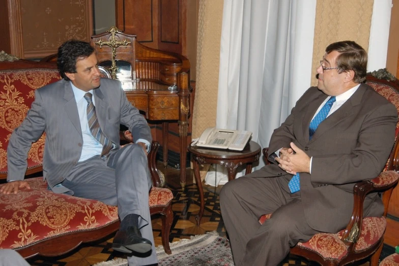 two men sitting next to each other in a room