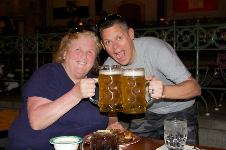 two people are holding their mugs full of beer