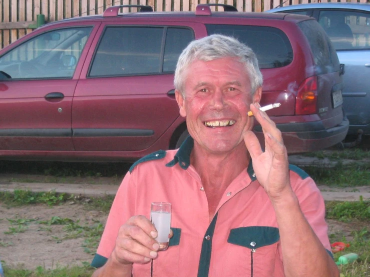 the man is smoking in front of a red car