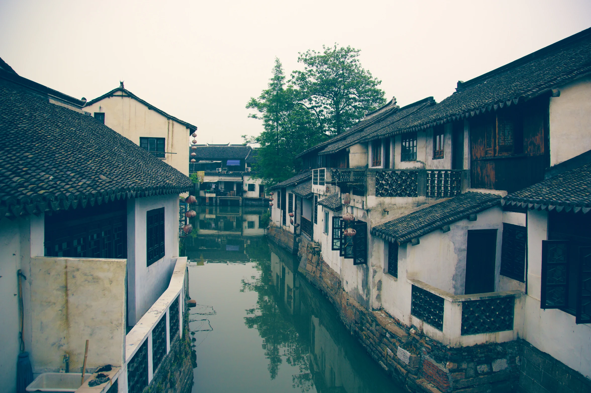 a river runs through a row of older buildings in a village