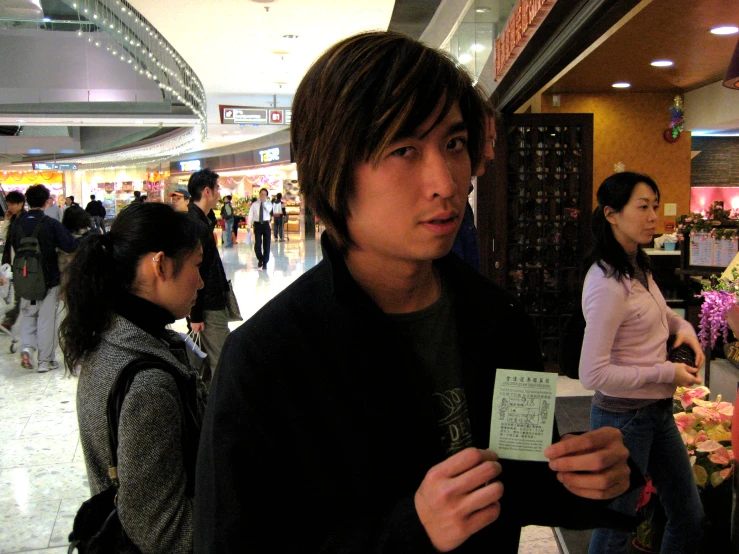 an asian man is holding his card with a name tag