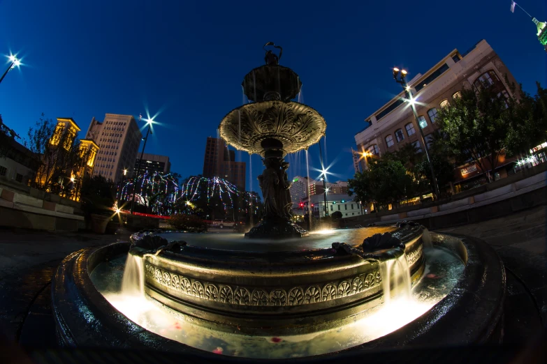 the water fountain at the side of a city street at night