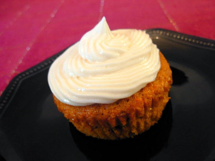 a cupcake topped with white frosting on a plate