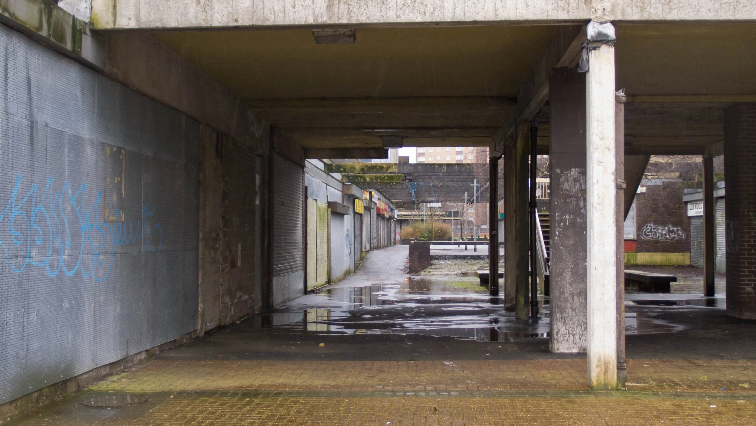 an empty sidewalk under a bridge with a lot of graffiti