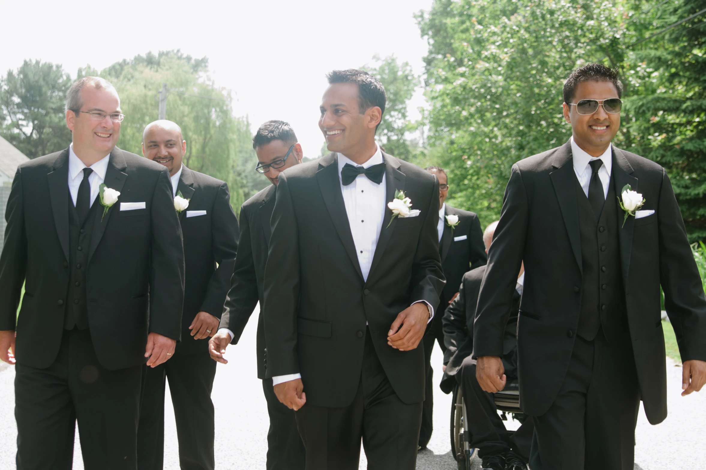 four men in tuxedo are walking with sunglasses on