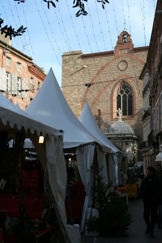 a white tent outside a large building and hanging cords