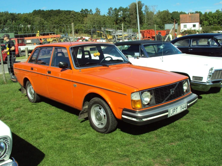 an orange and white station wagon sitting on top of a field