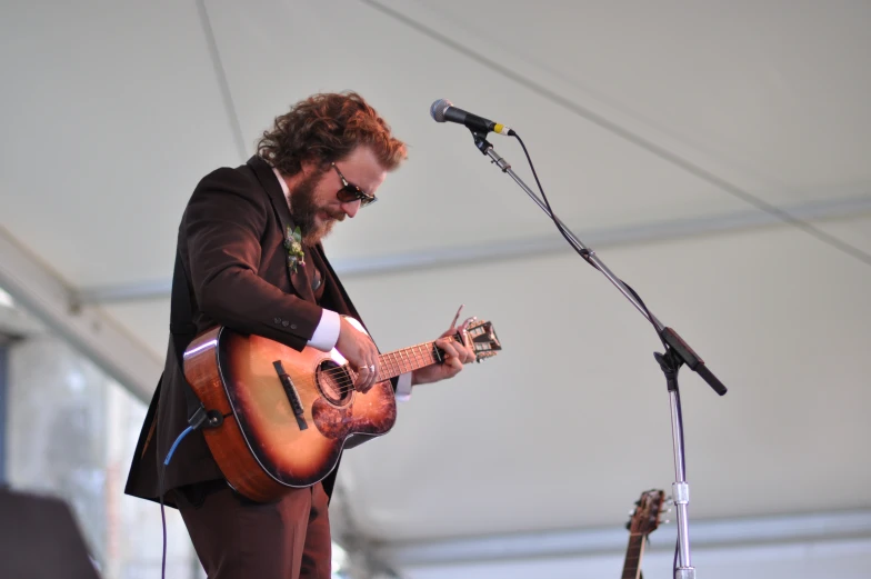 a man is playing an acoustic guitar at a festival