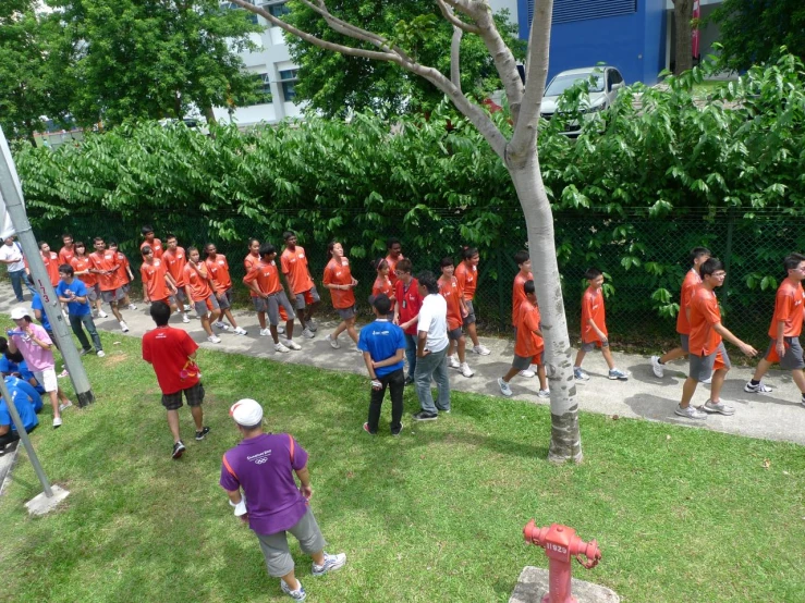 a bunch of people in orange shirts standing on the sidewalk