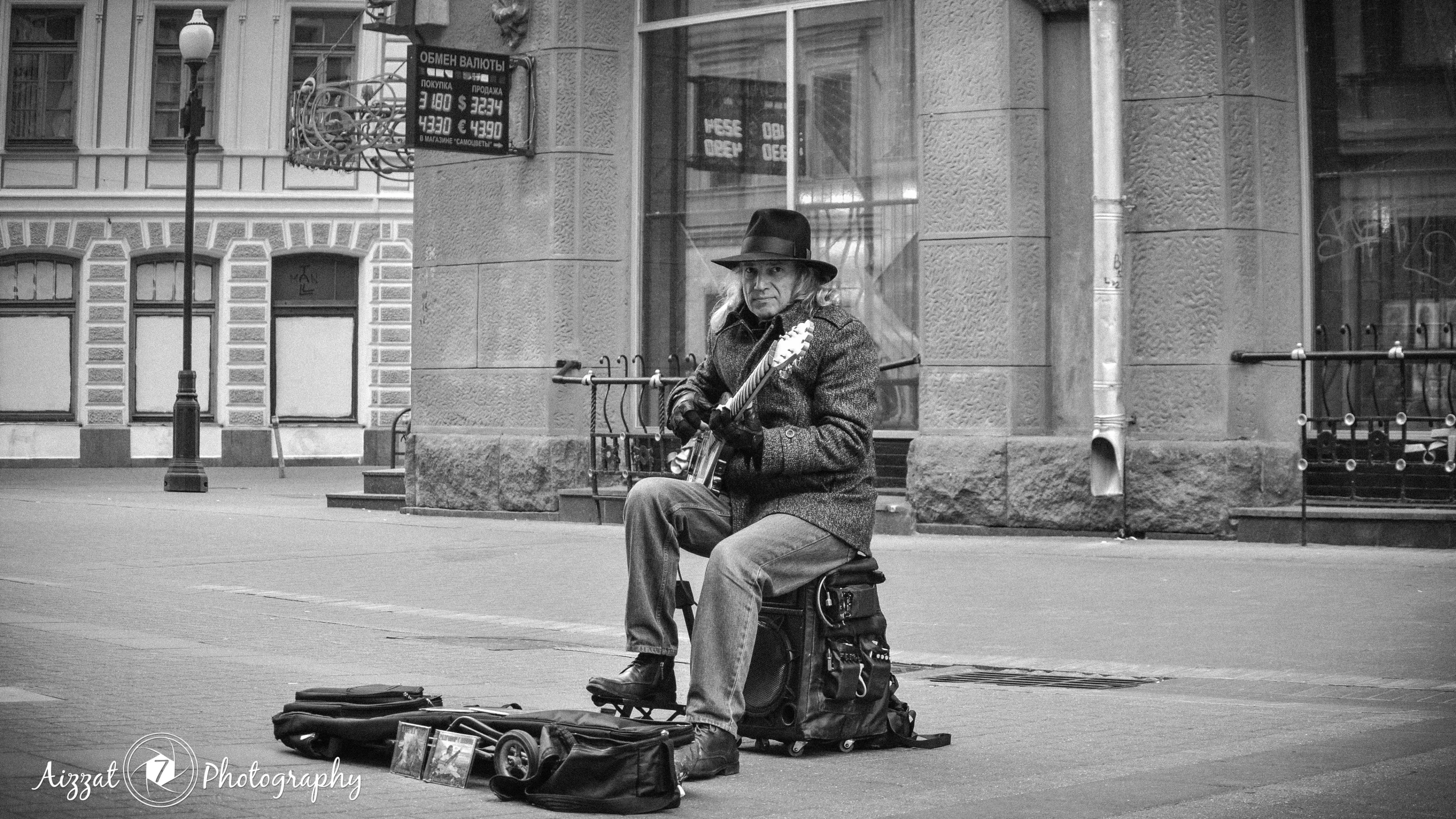 two people sitting on a city street in front of a building