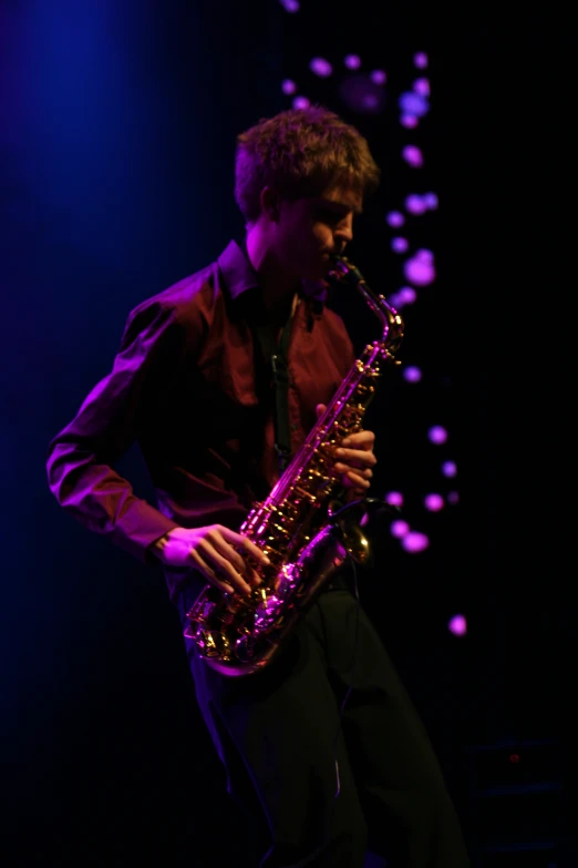 the man is holding a saxophone on stage