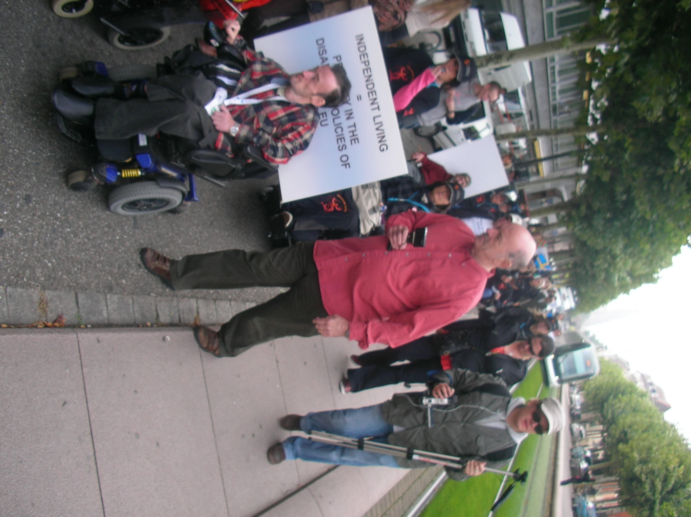 a group of people with microphones on street next to sidewalk