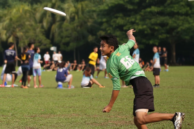 the young man is reaching up towards the frisbee